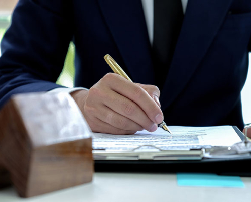 Person in suit signing paperwork